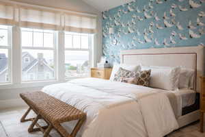 Primary bedroom featuring lofted ceiling, fireplace, and wallpaper