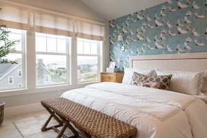 Primary bedroom featuring lofted ceiling, fireplace, and wallpaper