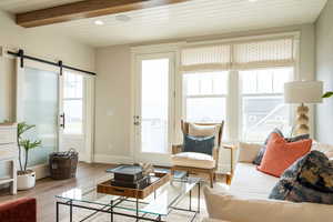 Living room with V-grooving and beamed ceiling, hardwood / wood-style flooring, and  wallpaper