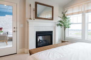 Primary bedroom featuring lofted ceiling, fireplace, and wallpaper