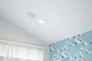 Primary bedroom featuring lofted ceiling, fireplace, and wallpaper