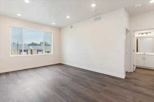 Empty room featuring a textured ceiling, dark hardwood / wood-style flooring, and sink