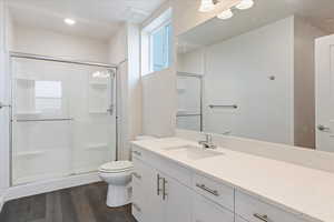 Bathroom featuring toilet, a shower with door, vanity, and wood-type flooring