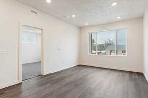 Spare room with a textured ceiling and dark hardwood / wood-style floors