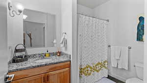 Bathroom featuring walk in shower, tile patterned flooring, vanity, and toilet