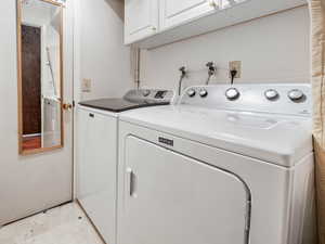 Laundry room featuring independent washer and dryer and cabinets