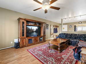 Living room featuring track lighting, ceiling fan, and light hardwood / wood-style flooring