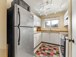 Kitchen featuring appliances with stainless steel finishes, white cabinets, and sink