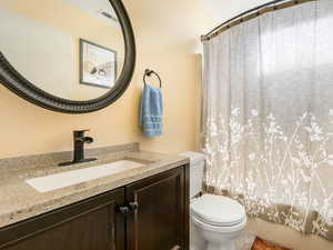 Full bathroom featuring toilet, vanity, and shower / bath combo with shower curtain