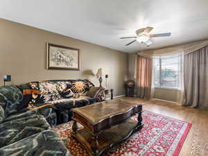 Living room with ceiling fan and light hardwood / wood-style floors