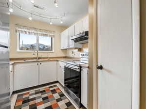 Kitchen with white cabinetry, electric stove, and sink