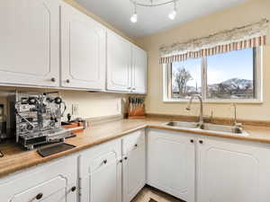 Kitchen featuring white cabinets, rail lighting, a mountain view, and sink