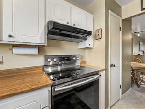 Kitchen featuring white cabinets, rail lighting, and stainless steel range with electric stovetop