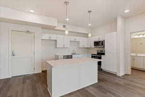 Kitchen with sink, white cabinets, a kitchen island, pendant lighting, and appliances with stainless steel finishes