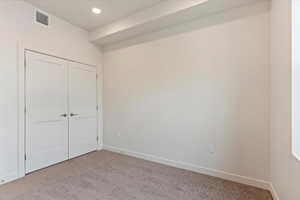 Unfurnished bedroom featuring a closet and light colored carpet