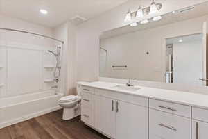 Full bathroom featuring toilet, shower / washtub combination, vanity, and hardwood / wood-style flooring