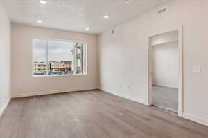 Unfurnished room with a textured ceiling and light wood-type flooring