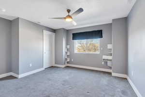 Carpeted empty room featuring a textured ceiling and ceiling fan