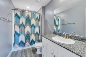 Full bathroom with hardwood / wood-style floors, toilet, vanity, and shower / bath combo