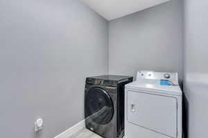 Laundry room featuring washing machine and dryer and light hardwood / wood-style flooring