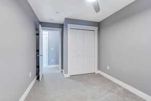 Unfurnished bedroom featuring a closet, ceiling fan, and light colored carpet