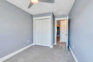 Unfurnished bedroom featuring ceiling fan, a closet, and light carpet