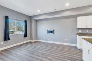 Kitchen featuring white cabinets, dark stone countertops, and light hardwood / wood-style flooring