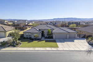 Single story home featuring a garage, a front lawn, and a mountain view