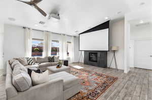 Cinema room featuring lofted ceiling, a tiled fireplace, and ceiling fan