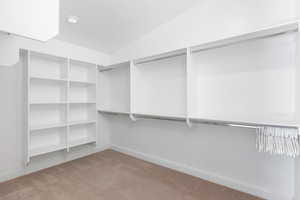 Spacious closet with lofted ceiling and light colored carpet