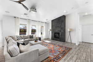 Living room featuring ceiling fan, vaulted ceiling, and a fireplace