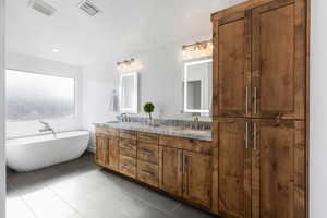 Bathroom featuring a tub to relax in, tile patterned flooring, and vanity