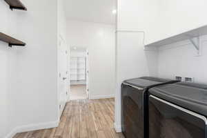 Clothes washing area with light hardwood / wood-style floors and washer and clothes dryer