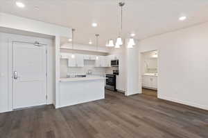 Kitchen with dark wood-type flooring, pendant lighting, white cabinetry, appliances with stainless steel finishes, and sink