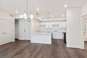 Kitchen featuring stainless steel dishwasher, dark hardwood / wood-style floors, hanging light fixtures, electric range, and white cabinetry