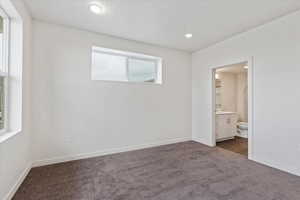 Unfurnished bedroom featuring dark colored carpet and connected bathroom