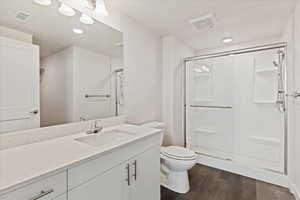 Bathroom with walk in shower, hardwood / wood-style floors, vanity, and toilet