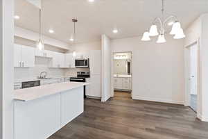 Kitchen with sink, appliances with stainless steel finishes, pendant lighting, and white cabinetry