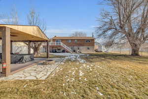 Back of house with a fire pit, a wooden deck, and a yard