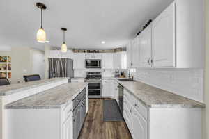 Kitchen featuring stainless steel appliances, white cabinets, pendant lighting, and sink