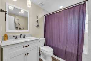 Full bathroom featuring toilet, hardwood / wood-style flooring, shower / bathtub combination with curtain, and vanity