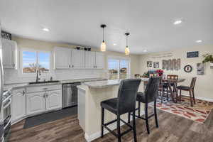 Kitchen featuring appliances with stainless steel finishes, white cabinets, a kitchen island, and sink