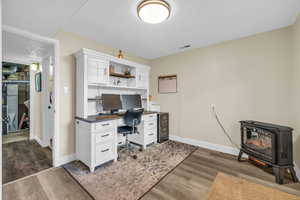 Home office featuring a wood stove and dark wood-type flooring