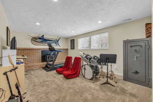 Workout area with brick wall, carpet flooring, and a textured ceiling