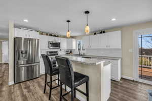 Kitchen featuring stainless steel appliances, a breakfast bar area, a center island, and white cabinetry