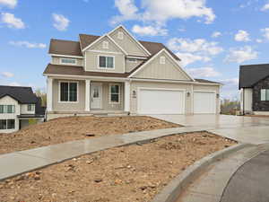 Craftsman-style house featuring driveway, board and batten siding, a shingled roof, covered porch, and a garage