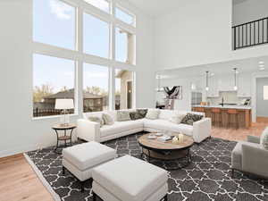 Living room with a towering ceiling, light wood finished floors, and baseboards