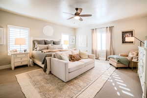 Bedroom featuring ceiling fan, multiple windows, and light carpet