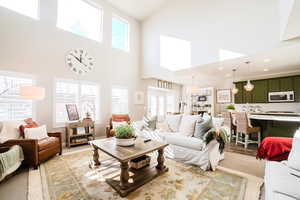 Living room featuring a high ceiling, light hardwood / wood-style floors, and plenty of natural light