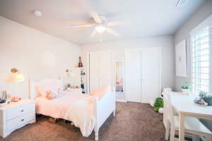 Bedroom with multiple closets, ceiling fan, and dark colored carpet